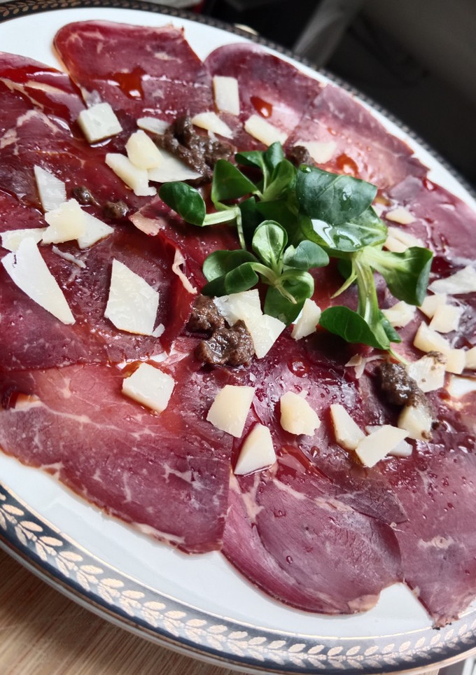 Una foto de Carpaccio de cecina con salsa de trufas y queso viejo tostado