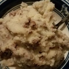 A picture of Mashed potatoes and hamburger meat with gravy.