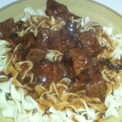 A picture of Beef tips with gravy over egg noodles.