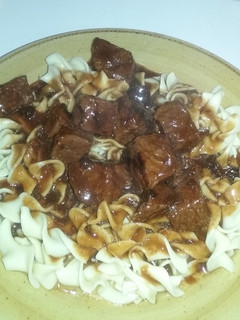 A picture of Beef tips with gravy over egg noodles.