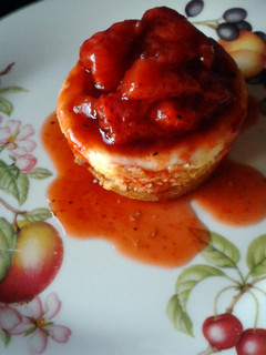 A picture of Vanilla Cheesecakes with Roasted Strawberry Sauce.