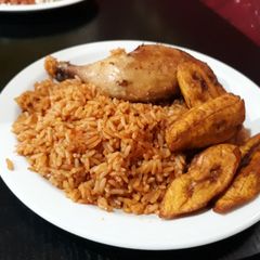 A picture of Jollof rice with fried plantain and grilled chicken.