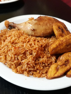 A picture of Jollof rice with fried plantain and grilled chicken.