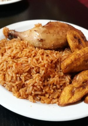 A picture of Jollof rice with fried plantain and grilled chicken.