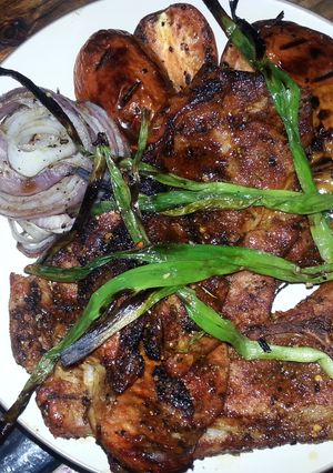 A picture of Grilled pork steaks with grilled veggies.