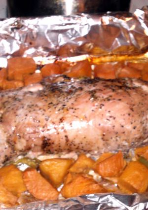 A picture of marinated pork tenderloin pepercorn and garlic with sliced sweet potatos.