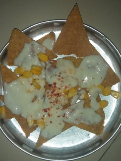 A picture of Nachos with cheese sauce.