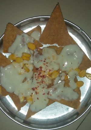 A picture of Nachos with cheese sauce.