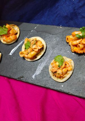 A picture of Indian gravy pasta with mini paratha bites.