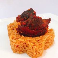 A picture of Jollof rice and fried goat peppered goat meat.