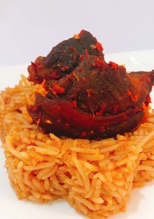 A picture of Jollof rice and fried goat peppered goat meat.