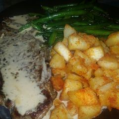 A picture of New York Steak with roasted garlic cream sauce, yucca root and stir fried green beans.