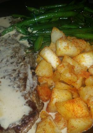 A picture of New York Steak with roasted garlic cream sauce, yucca root and stir fried green beans.