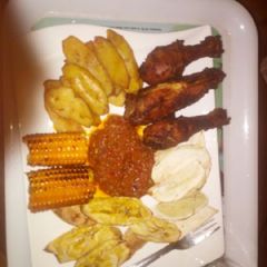 A picture of Fried plantain,Fried chicken,roasted corn with sauce.
