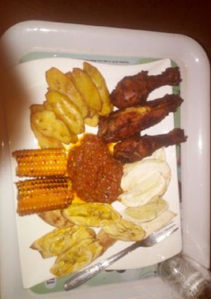 A picture of Fried plantain,Fried chicken,roasted corn with sauce.