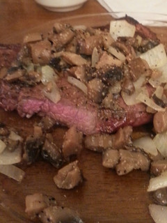 A picture of Grilled steak with sauteed mushrooms and onions.