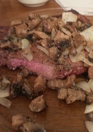A picture of Grilled steak with sauteed mushrooms and onions.