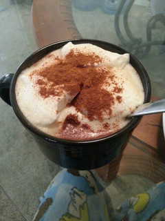 A picture of Coffee with cinnamon and whipped cream.