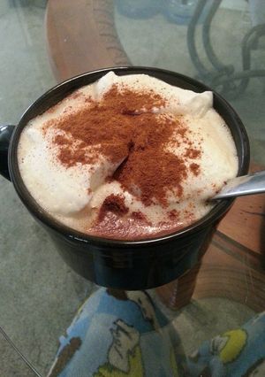A picture of Coffee with cinnamon and whipped cream.