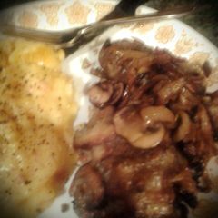 A picture of Smothered Chicken breast with onions and mushrooms & provolone cheese.