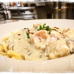 A picture of Shrimp and Scallops Shiitake, Mushroom, Bacon Cream Sauce over Pasta.