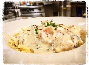 A picture of Shrimp and Scallops Shiitake, Mushroom, Bacon Cream Sauce over Pasta.