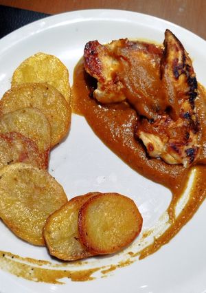 Una foto de Pollo con puré de calabaza, acompañado de papas