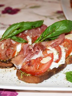 Une photo de Bruschettas au pesto, tomates, mozzarella et jambon cru