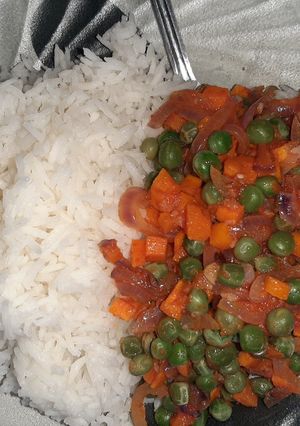A picture of White rice with green peas and carrot gravy.