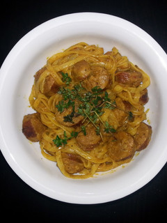 A picture of Rice noodle with curry sauce and sausage.