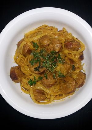 A picture of Rice noodle with curry sauce and sausage.