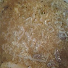 A picture of Liquid chicken soup with noodles.