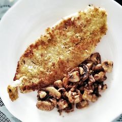 A picture of pan-fry fish with sauteed mushroom.