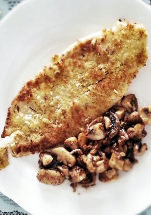 A picture of pan-fry fish with sauteed mushroom.