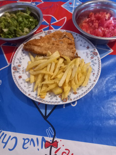 Una foto de Pescado y papas fritas con ensalada de lechuga y tomate