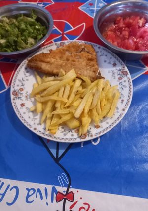 Una foto de Pescado y papas fritas con ensalada de lechuga y tomate