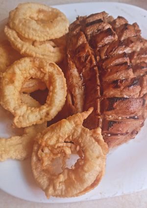 Una foto de Suprema grillé y aros de cebolla