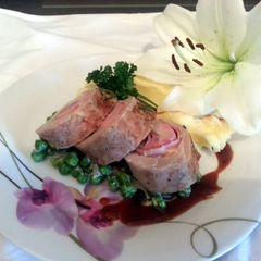 A picture of Smoked Cheddar wrapped in pork loin with French peas and plum sauce served with parmesan mashed potatoes.