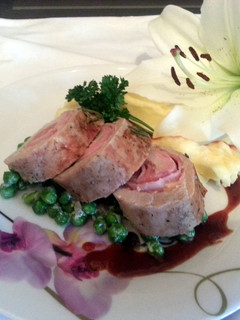 A picture of Smoked Cheddar wrapped in pork loin with French peas and plum sauce served with parmesan mashed potatoes.