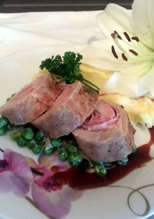 A picture of Smoked Cheddar wrapped in pork loin with French peas and plum sauce served with parmesan mashed potatoes.