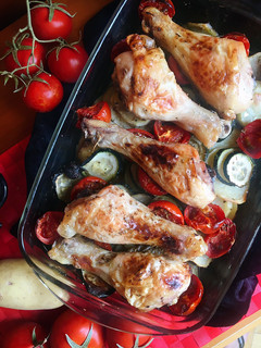 Una foto de Muslos de pollo al horno con calabacín, patatas y tomate