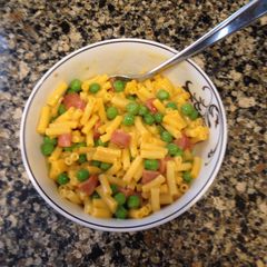 A picture of Mac & Cheese with Peas and Hot Dogs.
