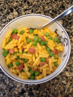 A picture of Mac & Cheese with Peas and Hot Dogs.