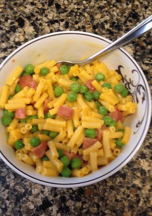 A picture of Mac & Cheese with Peas and Hot Dogs.