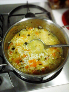 A picture of Risotto rice soup with green zucchini and tomato.