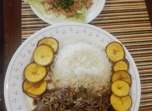 Una foto de Ropa Vieja a mi estilo, acompañada de arroz blanco, monedas de plátano verde con cáscara y ensalada