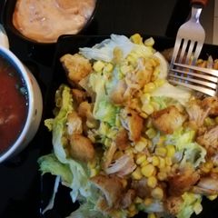 A picture of Nachos salad with salsa dip sauce.