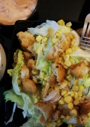 A picture of Nachos salad with salsa dip sauce.