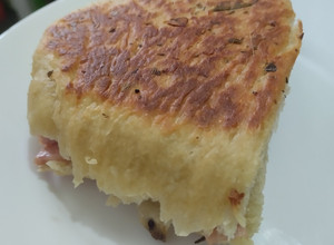 Una foto de Sándwich🥪de salchichón de cerdo🥓y queso🧀en pan🍞casero de ajo🍖y finas hierbas🥐🌿🧄