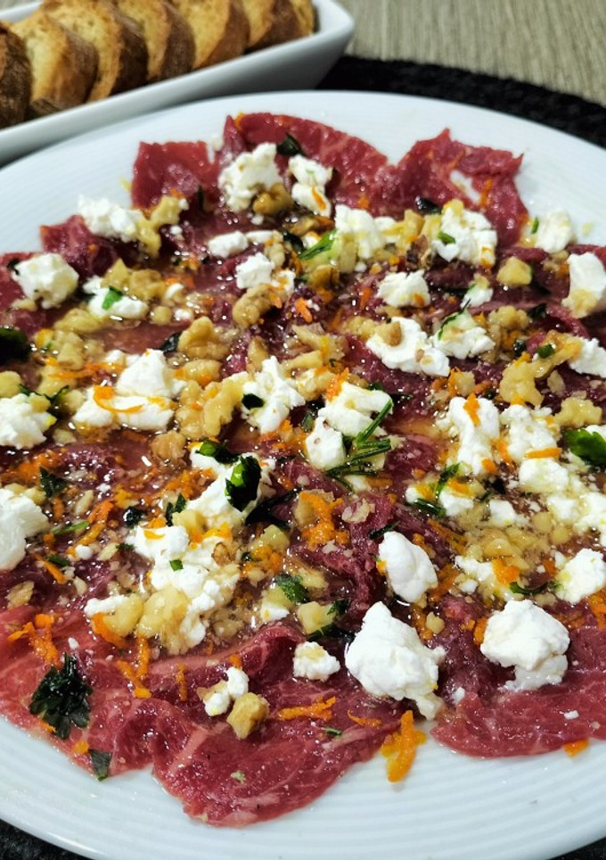 Una foto de Carpaccio de ternera con queso de cabra y aliño de naranja y miel